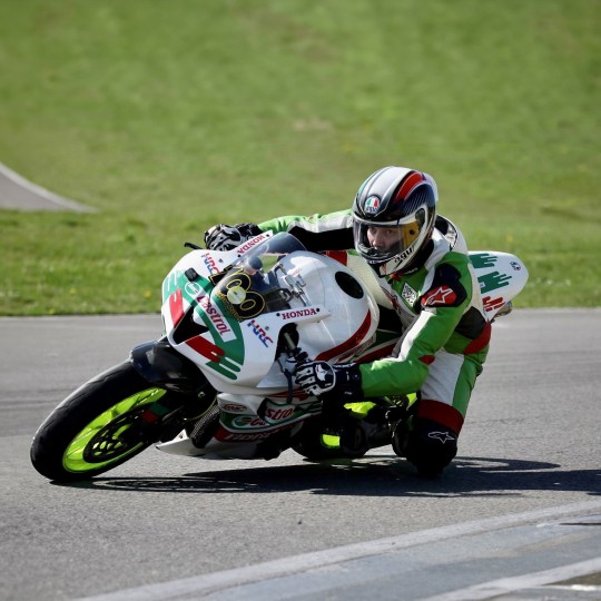 Adam Parry photographed taking a sharp corner on his bright green motorbike.